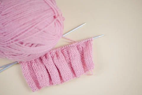 A soft pink knitting project with needles and yarn for a cozy, handmade war.. Stock Photos