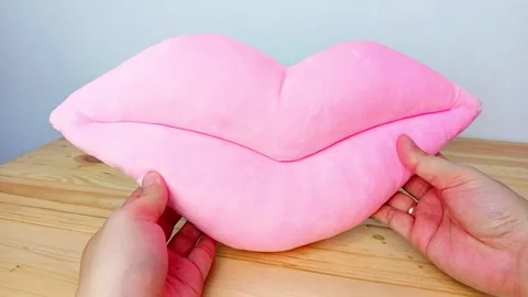 Soft Pink Lip-Shaped Pillow on Wooden Surface Stock Footage 287798450