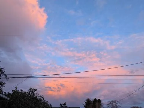 Soft pink-tinted clouds drift across layered blue skies with hints Stockfoto's