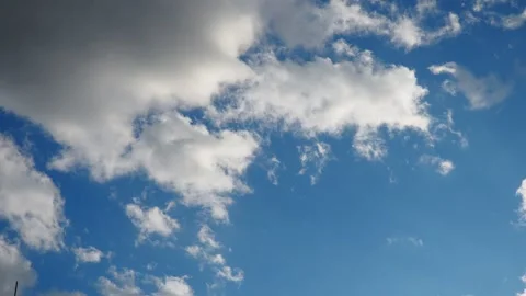 Soft puffs of clouds swirl and shift against a brilliant blue sky Stock Footage 331463994