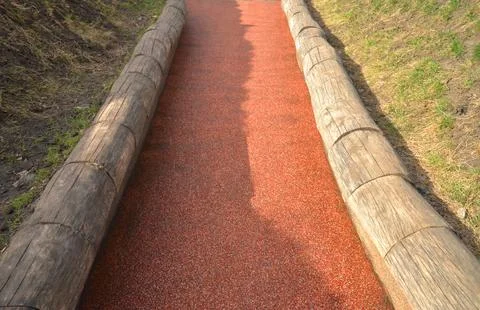 Soft red colored bicycle path (road) framed by wood, closeup Stock Photos