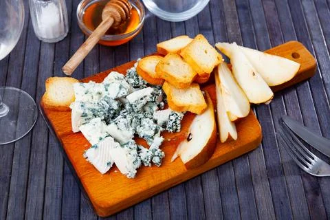 Soft roncari blue cheese with pear, croutons and honey on wooden board Stock Photos