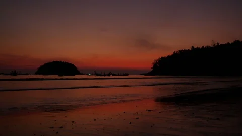 Soft sea wave breaking sand beach, silhouette tree mountain on right, island  Stock Footage 126756407