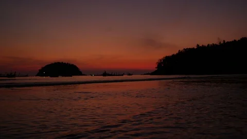 Soft sea wave breaking sand beach, silhouette tree mountain on right, island Stock Footage 126774037