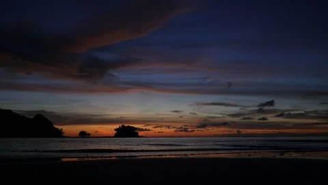 Soft sea wave breaking sand shore beach, silhouette mountain and island, clou Stock Footage 128299316