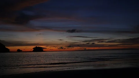 Soft sea wave breaking sand shore beach, silhouette mountain and island, clou Stock Footage 128299672