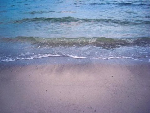 The soft sea waves gently roll on the sandy beach. Beautiful picture of dawn Stockfoto's