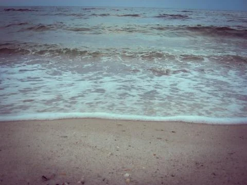 The soft sea waves gently roll on the sandy beach. Beautiful picture of dawn Stock Photos