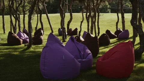 Soft seating for relaxation stands in the shade of trees on the lawn in the park Stock Footage 344755288