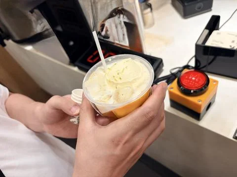 Soft serve ice cream in a plastic cup with a red button. Stock Photos