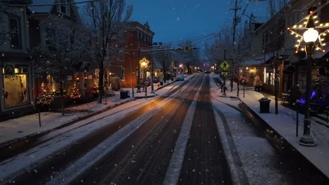 Soft Snowfall over small American town at dusk, with warm Christmas lights Vídeo Stock 327440516