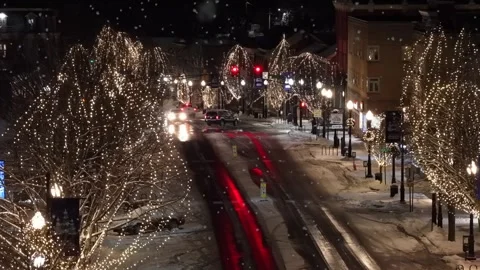 Soft snowfall in small American town with decorated lighting trees along Main Stock Footage 331339915