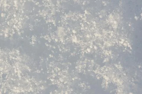 Soft snowflakes drift gently over a pale, textured surface Stock Photos