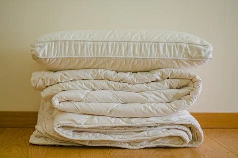 Soft stack folded blanket and pillows on the wooded floor in room Stock Photos