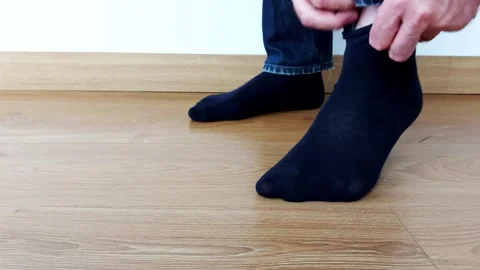 Soft Start: Slipping Into Black Socks on Warm Wooden Floor Video stock 315285779