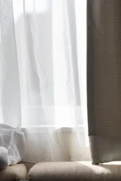 Soft sunlight filtering through white gauze curtains onto the sofa Stock Photos