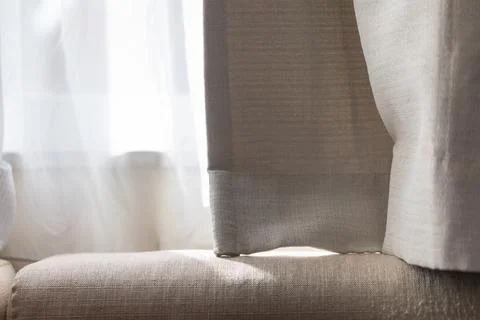 Soft sunlight filtering through white gauze curtains onto the sofa Stock Photos