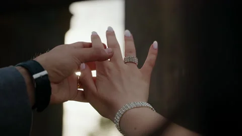 Soft sunlight filters through intertwined hands of newlywed couples Stock Footage 264587884