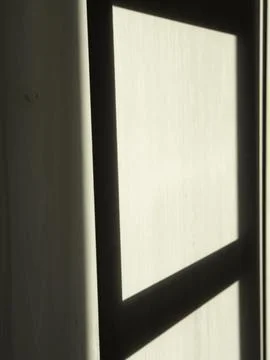 Soft sunlight filters through a window frame Stock Photos