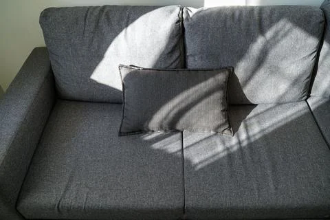 Soft sunlight on modern grey sofa. Stock Photos