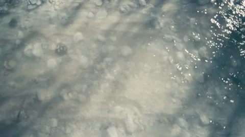 Soft sunlight patterns under clear water with stones and gentle ripples. Almost Stock Footage 333797514