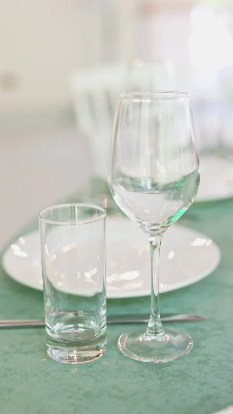 Soft sunlight reflects off empty glassware on a green tablecloth Stock Footage 335579891