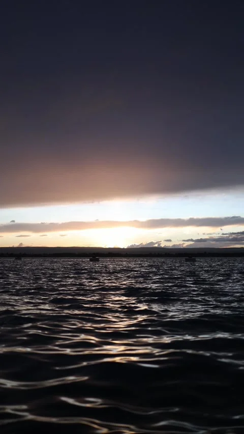Soft sunset fading over rippling dark water with calm distant horizon Stock Footage 327924443