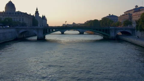 Soft sunset light bathes the calm Seine River as it flows under ancient Stock Footage 313350073