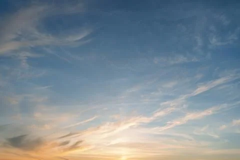 Soft sunset washes wide sky with wispy clouds and warm horizon glow, calm Stock Photos
