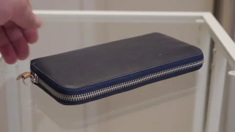 Soft Thud: Hand Drops Blue Leather Zippered Clutch onto Glass Table. Stock Footage 320808273