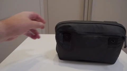 Soft Thud as Hand Sets Black Fabric Tech or Travel Pouch on White Table Stock Footage 321268031