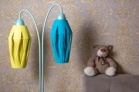 Soft toy bear sits on the back of the sofa next to a vintage floor lamp Stock Photos