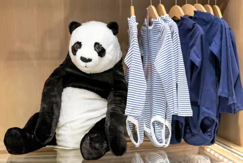 Soft toy panda bear on the background of children's clothing. Stock Photos