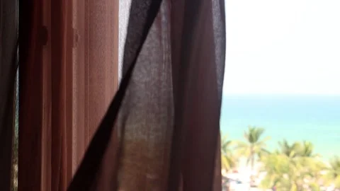 Soft transparent curtains blowing before a window with a view of the sea Stock Footage 341436305