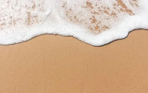 Soft wave and white bubble on brown sand on the beach Stock Photos