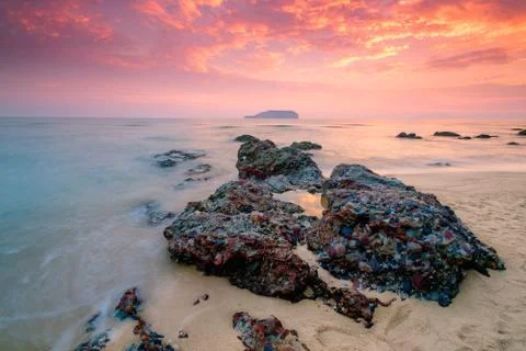Soft wave of blue ocean on sandy beach during sunrise as background. Soft wav Stock Photos