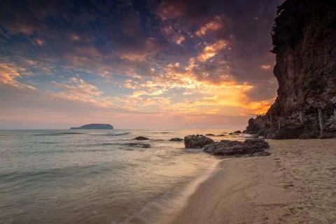 Soft wave of blue ocean on sandy beach during sunrise as background. Soft wave o Stock Photos
