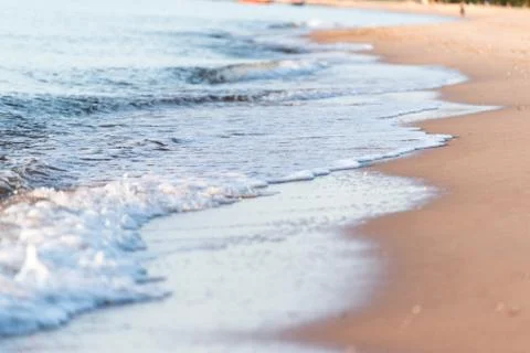 Soft wave of blue ocean on sandy beach in the morning. Stock Photos