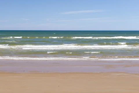 Soft wave of blue ocean on sandy beach in summer season. Stock Photos