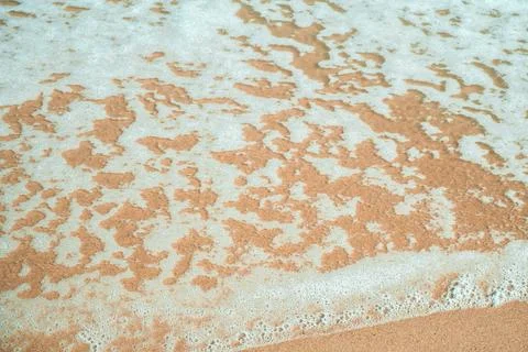 Soft wave of blue ocean on sandy beach. Background. Sand Texture. Brown san.. Stock Photos