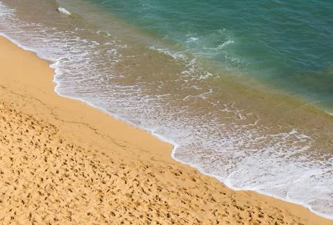 Soft wave of blue ocean on sandy beach. Background. Stock Photos