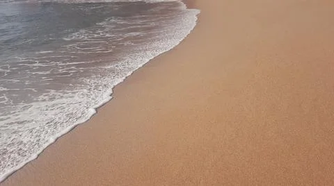 Soft wave on sandy beach during sunny summer day Stock Photos