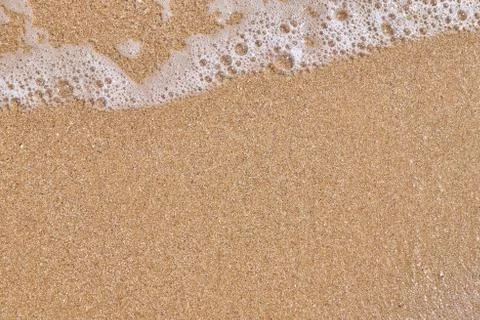 Soft wave of the sea on the sandy beach as background Stock Photos