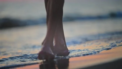 Soft waves and barefoot steps on sandy beach during colorful sunset, cinematic Stock Footage 335422361