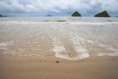 Soft waves and sandy beach of Tropical beach with mountain and cloud. Stock Photos