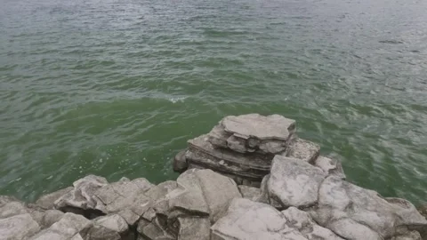 Soft waves crashing against the rocks on the edge of the lake Stock Footage 307415382