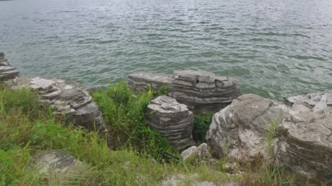 Soft waves crashing against the rocks on the edge of the lake Video stock 307416158