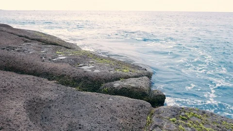 Soft waves of crystal blue water splash on rocky shore. Stock Footage 99771076