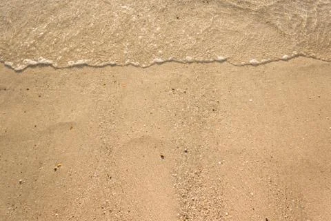 Soft waves with foam of ocean on the sandy beach background Stock Photos