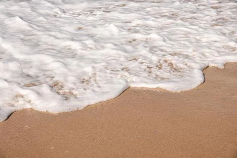 Soft waves with foam of ocean on the sandy beach background Stock Photos